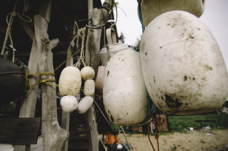 close up and selective focus group of white buoy tied with rope, hanging under wooden cottage over blurred backgroundの写真素材