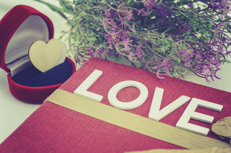 word LOVE made from wood on red gift box with ribbon made from recycle paper.artificial flower and ring caseの写真素材