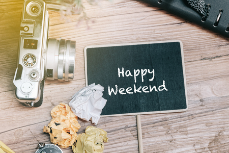 HAPPY WEEKEND word concept with vintage camera, crumple paper,compas and planner book on wooden floor.の写真素材