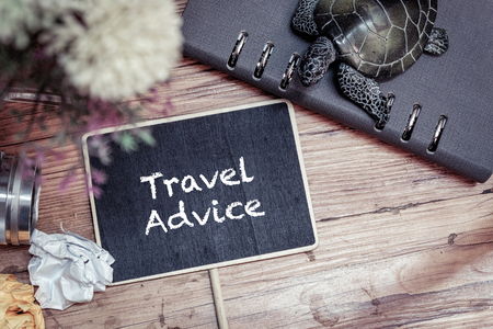 TRAVEL ADVICE word over travel and vacation concept.Top view vintage camera, crumple paper,compass and planner book layout on wooden floor.の写真素材