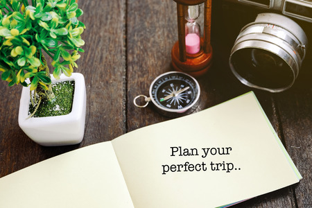 conceptual image with PLAN YOUR PERFECT TRIP word block with light effect.vintage camera, compass, coins in jar and wooden backgroundの写真素材