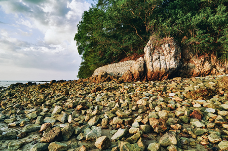 Seascape view and beach covered by stone over cloudy skyの写真素材