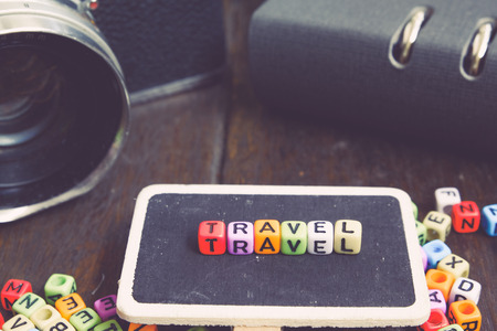 vacation and holiday concept with TRAVEL word block on wooden signage and vintage camera.faded effect colorの写真素材