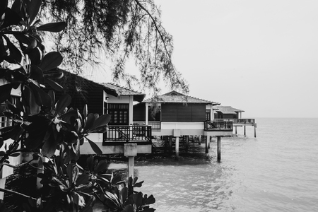 Black and white image of floating house near the beach, soft wave hitting the shore and cloudy skyの写真素材