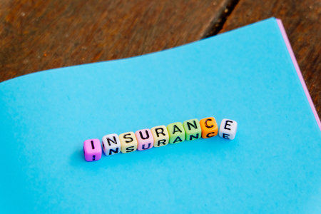 conceptual image with INSURANCE word block on note pad over wooden backgroundの写真素材