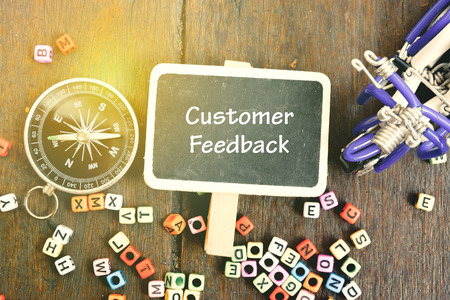 CUSTOMER FEEDBACK word for coaching and education concept with flat lay view wooden signage,compass and handcrafted item on wooden background with alphabetical block.の写真素材