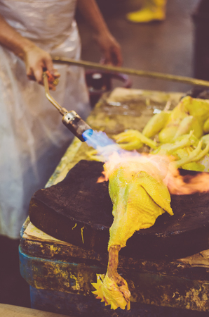 defocus shot and blur image, a worker using blowtorch to baked raw chicken before poultry process with grain effectの写真素材