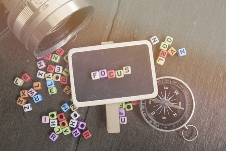 word block FOCUS on signage over wooden background, vintage camera with sunlight flare ideal for business and education conceptの写真素材
