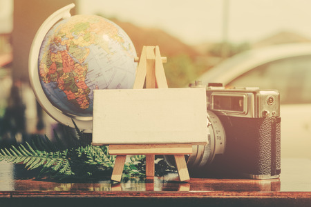 copy space,flat lay composition of vintage camera,compass, green plant and word block on wooden table ideal for vacation and travel conceptの写真素材