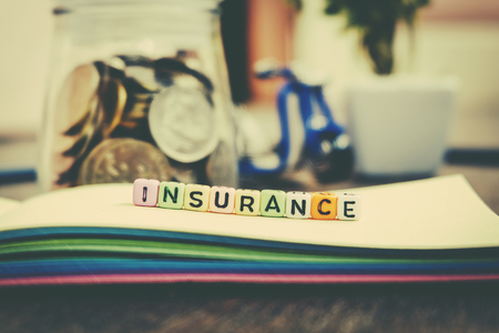 word block INSURANCE on colorful book over coin in jar background with retro color effectの写真素材