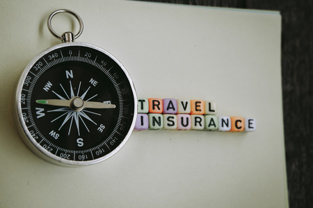 TRAVEL INSURANCE word blocks on yellow paper with compassの写真素材