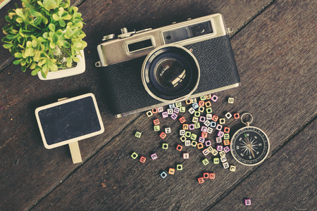 flat lay composition of vintage camera,compass, green plant and word block on wooden table ideal for vacation and travel conceptの写真素材