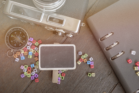 copy space of flat lay composition of vintage camera,compass, planner book and word block on wooden table ideal for vacation and travel conceptの写真素材