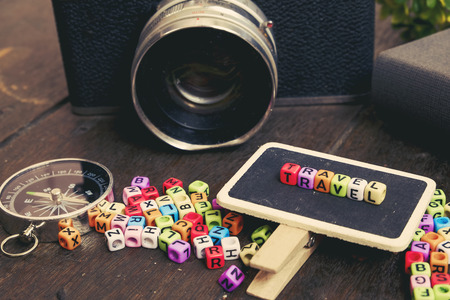 Prepareation before vacation, TRAVEL word block on signage, compass, vintage camera on wooden backgroundの写真素材