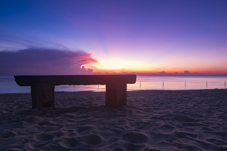 wooden bench over beautiful tropical beach and magical twilight sunrise background at dawn