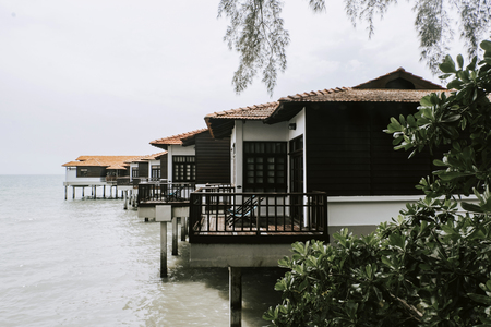 Travel holiday attraction, wooden modern design hotel on water over cloudy sky background.の写真素材