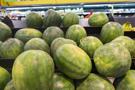 Fresh watermelons arranged on shelf for customer selection in hypermarketの写真素材