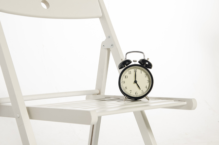 Vintage alarm clock on chair ideal for concept of measuring passing time, waiting,deadlines and time managementの写真素材