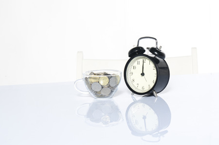 preparation and time management concept. vintage clock and coin on table with reflectionの写真素材