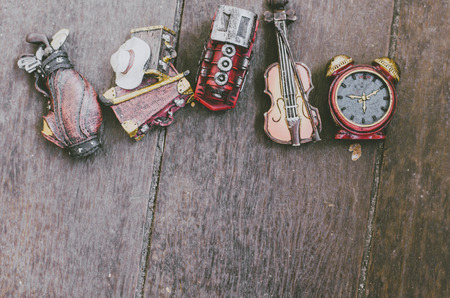 hobby and leisure object concept image, miniature violin, clocks,travel bag and train on wooden floorの写真素材