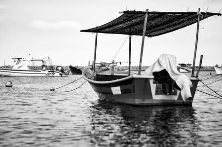black and white image of traditional fisherman boat moored over beautiful sea view at sunny dayの写真素材