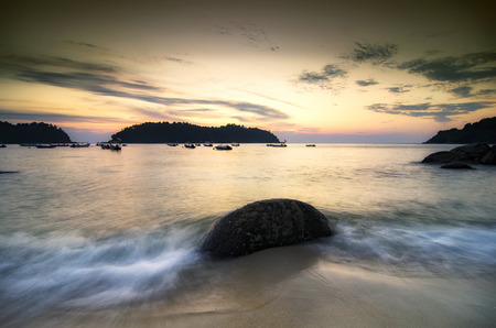 Background image, soft wave hitting the rock on the tropical beach over magical sunlight colorの写真素材