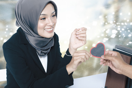 conceptual image,romantic look hand holding heart symbol made from wood over blurred backgroundの写真素材