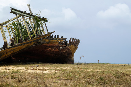 Abandon shipwreck near the sea shore under blue sky background and bright sunの写真素材