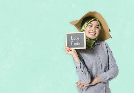 portrait young woman holding chalkboard with word love travelの写真素材