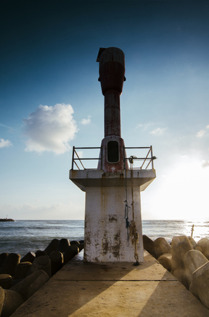 lighthouse and beautiful sea view scenery over stunning sunrise background.sunlight beam and soft wave hitting water break structureの写真素材