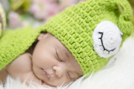 Portrait of sweet newborn baby in knitted snail costume sleeping on white blanket.selective focus shotの写真素材