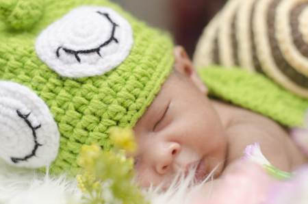 Portrait of sweet newborn baby in knitted snail costume sleeping on white blanket.selective focus shotの写真素材