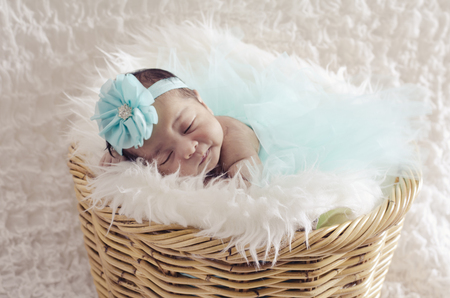 portrait of cute and adorable newborn baby with  head band sleeping in basket covered with furry mat.motherhood and parenting concept.の写真素材