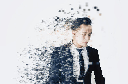 young businessman with dispersing and disintegrating into particles effect over white backgroundの写真素材