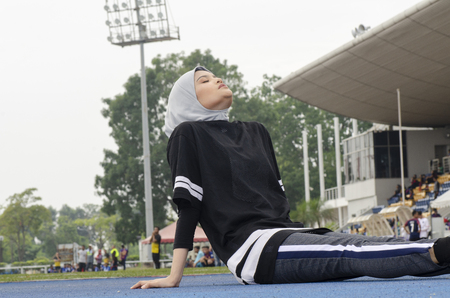 Sport and healthy lifestyle concept. young athlete with hijab stretching and warming up before runningの写真素材