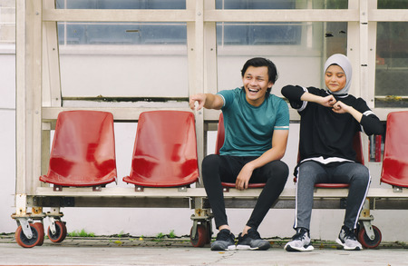 young couple sit in stadium with happy face expression, having fun and cheering to their teamの写真素材