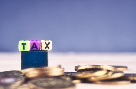 financial concept, colorful cube with word TAX and stacking coin on wooden tableの写真素材