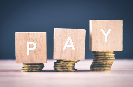 financial concept, Wood cube with word PAY and stacking coin on wooden tableの写真素材