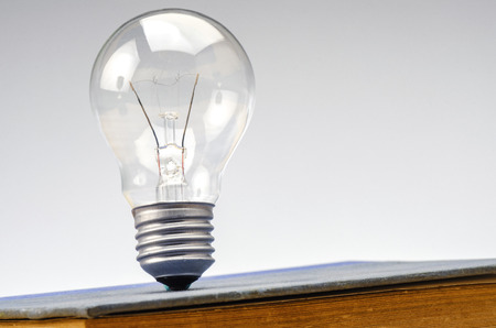 Education success and innovation concept, closeup shot image of light bulb on retro book over gray backgroundの写真素材