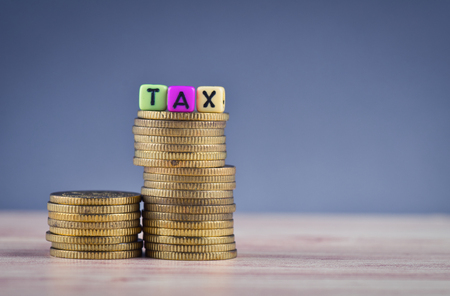 financial concept, colorful cube with word TAX and stacking coin on wooden tableの写真素材