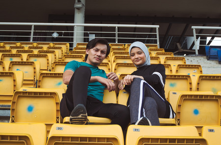 portrait of young sportsman and woman sitting and talking each otherの写真素材