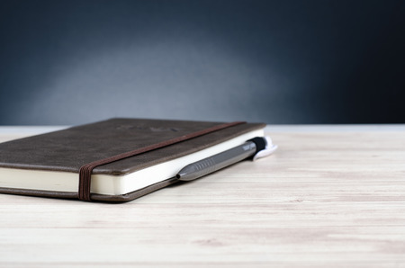 Mockup closed diary with pen on wooden background.selective focus shot,copy space for text.