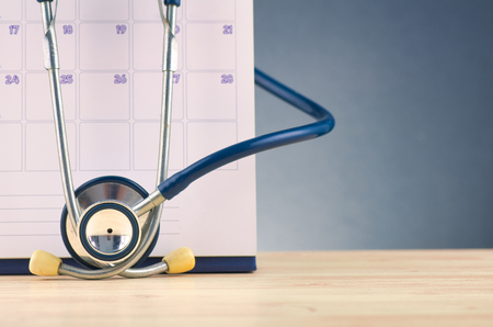 calendar and stestoscope over gently lit dark background for insurance and healthy lifestyle conceptの写真素材