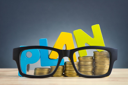 financial planning concept,word PLAN and stacking coins on wooden desk over beautiful reverberation gradient backgroundの写真素材