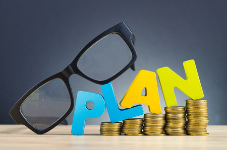 financial planning concept,word PLAN and stacking coins on wooden desk over beautiful reverberation gradient backgroundの写真素材