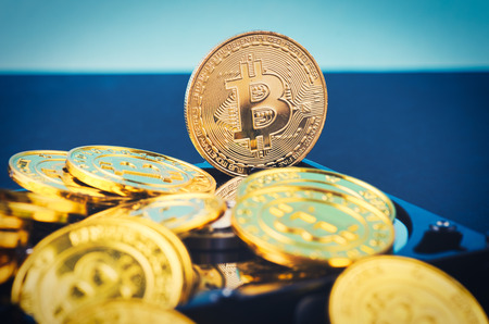 Virtual Cryptocurrency and Blockchain Technology concept, golden bitcoin on dismantle hard disk over gently lit dark background and light rayの写真素材