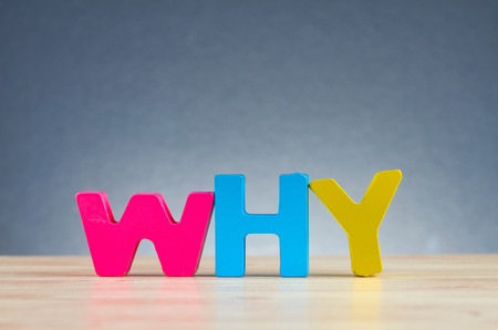 The word WHY spelled using wooden alphabet on desk over  gently lit dark background for information gathering or problem solving conceptの写真素材
