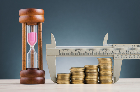 saving money concept,vernier caliper and stacking coins on wooden desk over beautiful reverberation gradient backgroundの写真素材