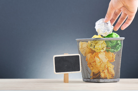 cropped hand putting crumple paper into bin for inspiration and innovation conceptの写真素材
