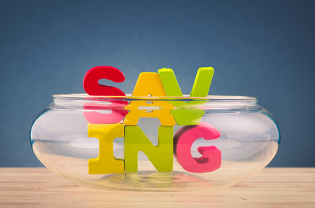 Financial crisis concept, empty glass jar piggy bank containing word SAVING on wooden deskの写真素材
